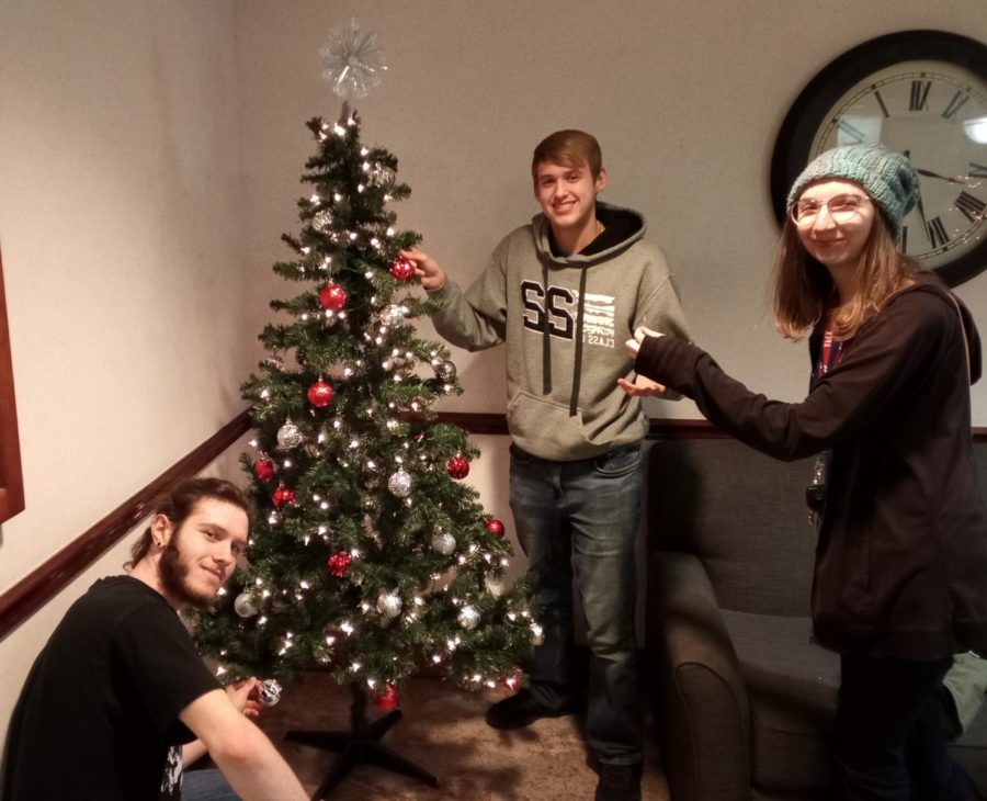 Hannah Woodhouse, Clay Edwards, and Brandon Brown spend time hanging ornaments on their tree together while discussing what they asked Santa for this holiday season.
