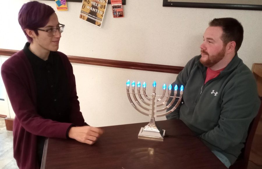 Ryan Moses, freshman history major, and Jay Mayes, Student Life and Housing Coordinator, discuss Hanukkah’s history and traditions by the menorah. 