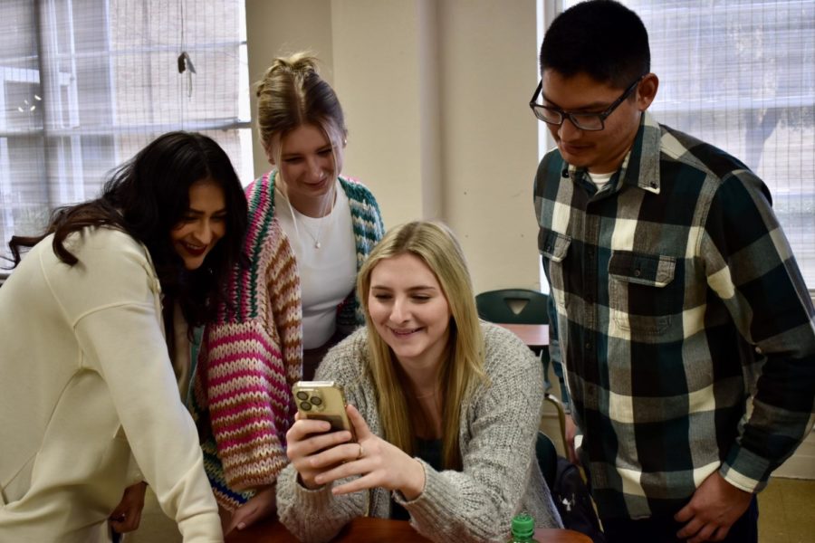 After class, Gisela Alonso, Addysyn Asmus, Lainey Morrow, and Paul Tointigh gather around to laugh at a TikTok video. 