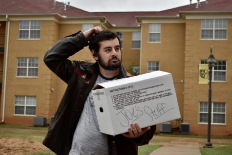 Joe Mitchell scratches his head in confusion while carrying a box of his things around the Lawson apartments. 