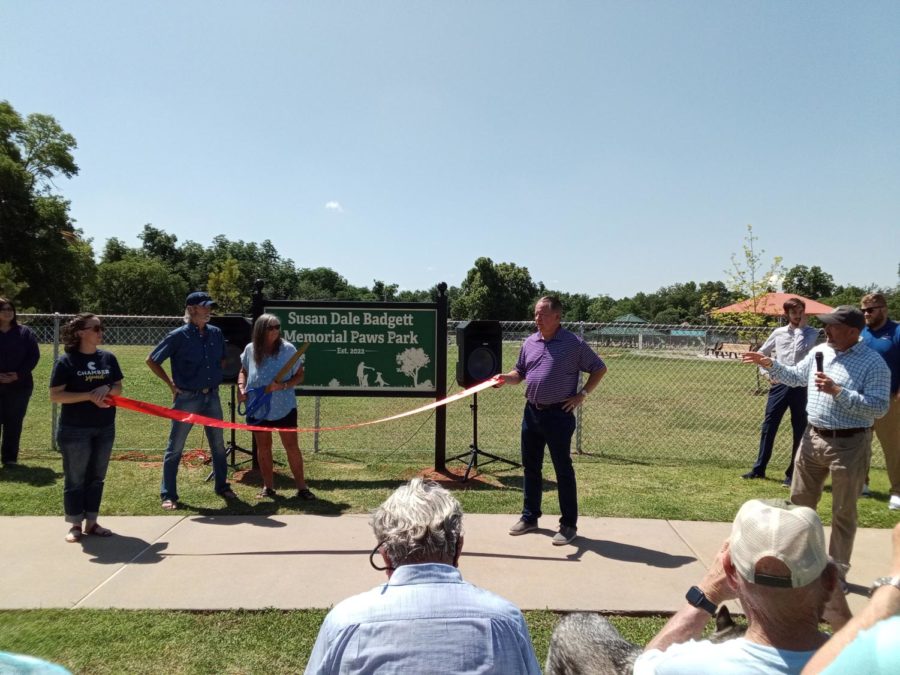 Chickasha’s Mayor Chris Mosely gives a dedication as Gail Ulrich prepares to cut the ribbon, marking the grand opening of the Susan Dale Badgett Memorial Paws Dog Park. 