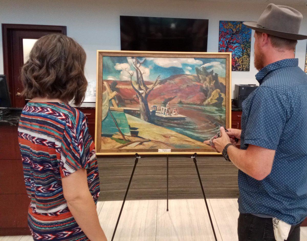 Shanna Couch (left) and Cody Couch (right) admire a work of art by late artist Leonard Good. The two also provided live music inside of the First National Bank during the art walk. 
