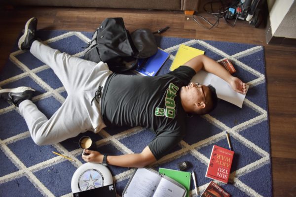 After exhausting himself with various responsibilities, Paul Tointigh crashes on his living floor, surrounded by a mess of homework, papers, books, and a planner.