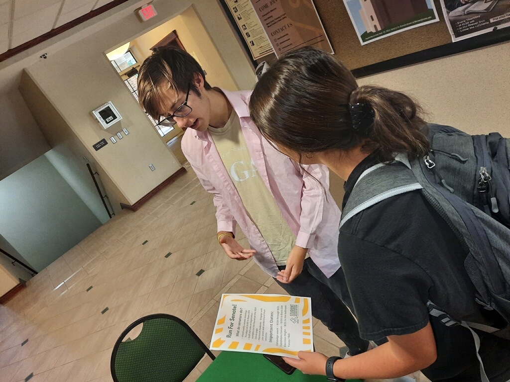 Ryan Moses, SGA vice president, communicates details about SGAs upcoming election night to Emily Loughridge.