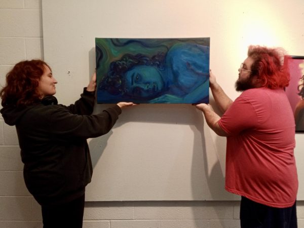 Destiny Miller (left) and Zeke Simon hang pieces on the third floor of Davis Hall in preparation of their show, “Agoraphobia.”