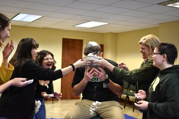 Bella Wilson, Hayla Wilson, Chloey Orosco, Dr. Hale, and Luke Messick push a pie into Sheppard McConnells face during an SAB event. 