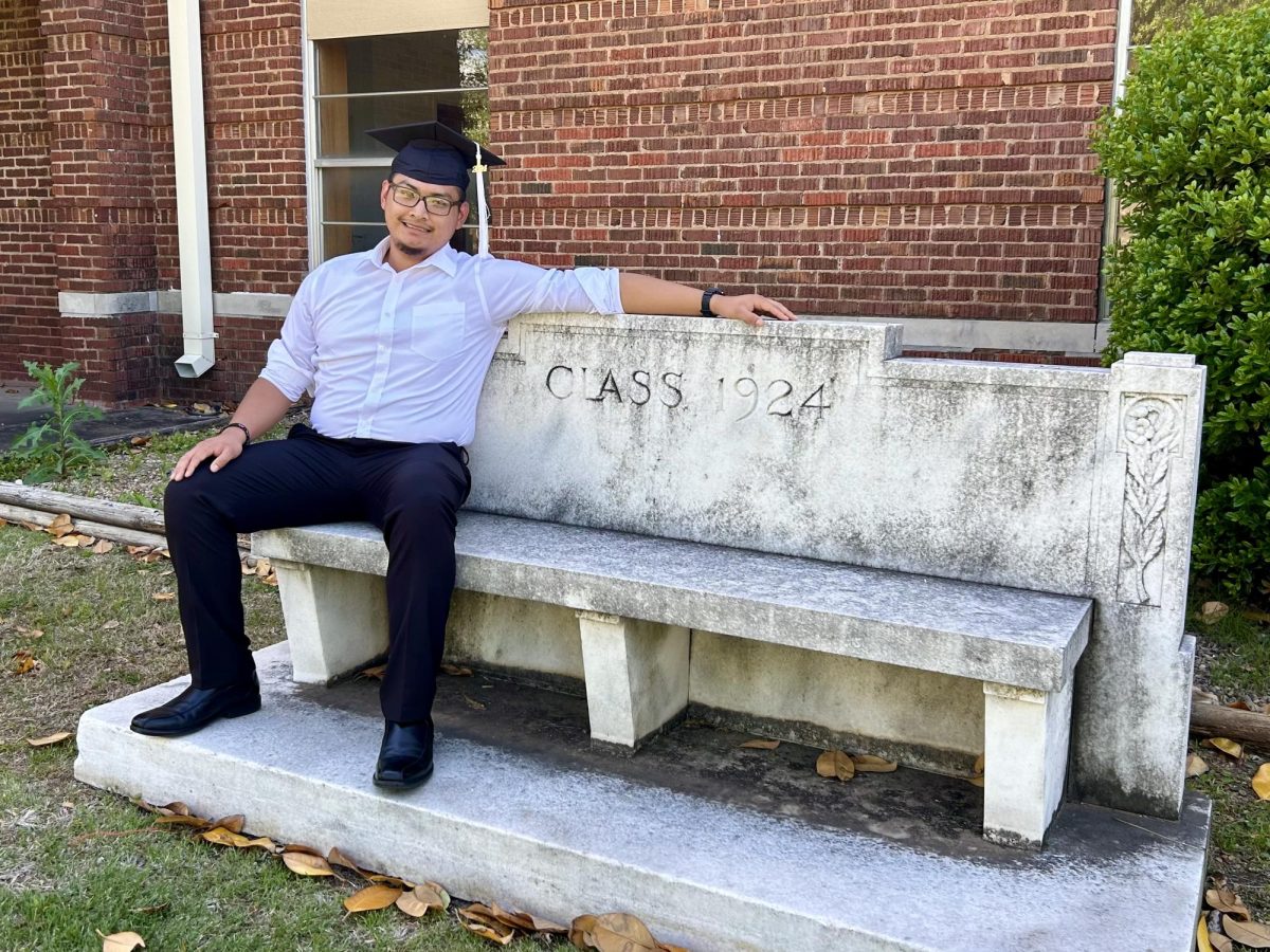 Senior Paul Tointigh sits on an OCW bench from 1924 and excitedly awaits for his 2024 bench to be placed nearby. 