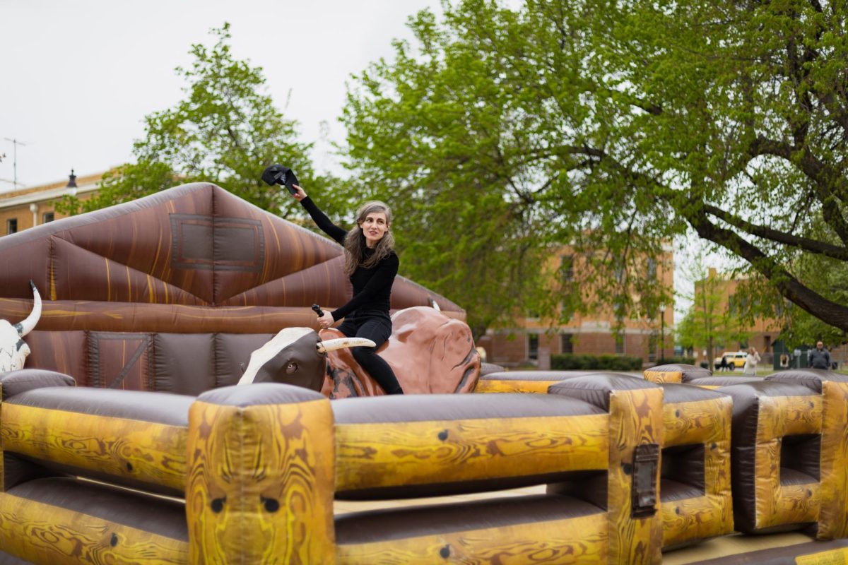 Dean of the School of Visual and Performing Arts Jordan Vineyard takes a ride on the mechanical bull inflatable. 
