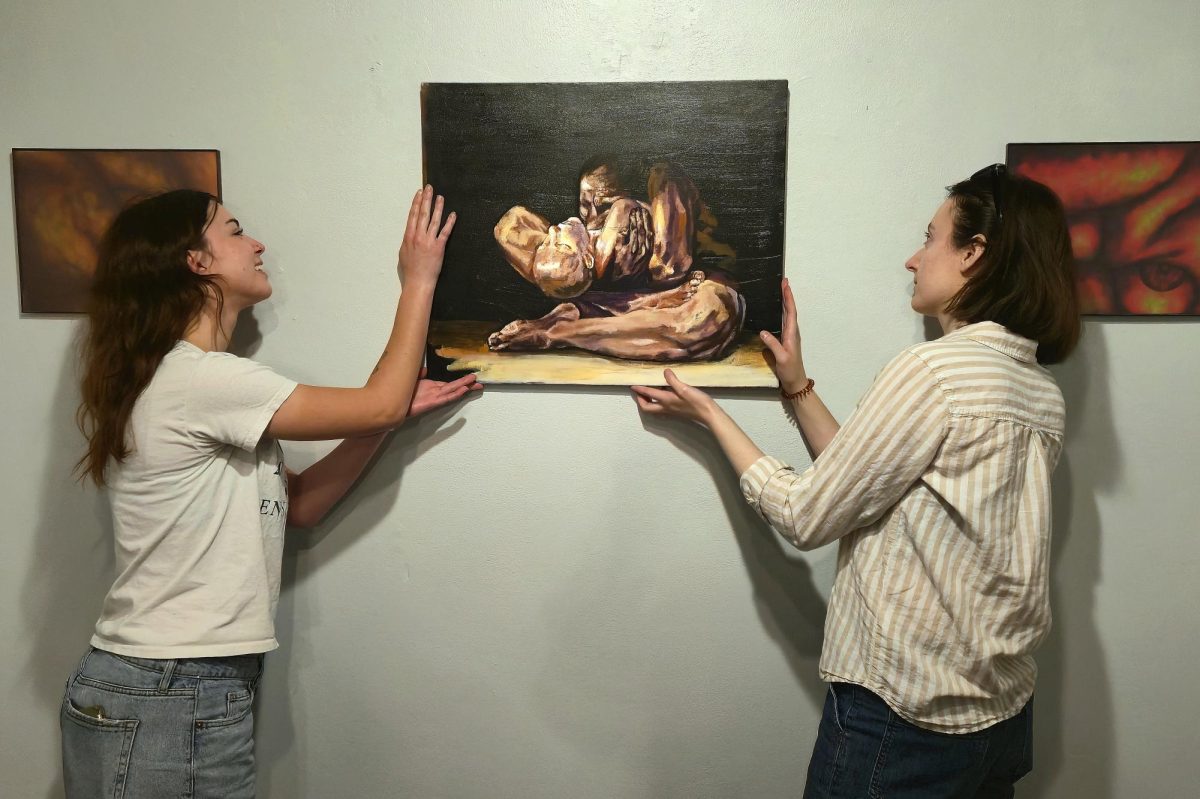 Abbey Ummel (left) and Julia Taylor hang works for the "Rational Animal" show in the Nesbitt Gallery in Davis Hall.