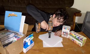 Raydan Thomas-Lapham, Communication senior and Event Director, drills holes into cap squares for seniors to decorate. 